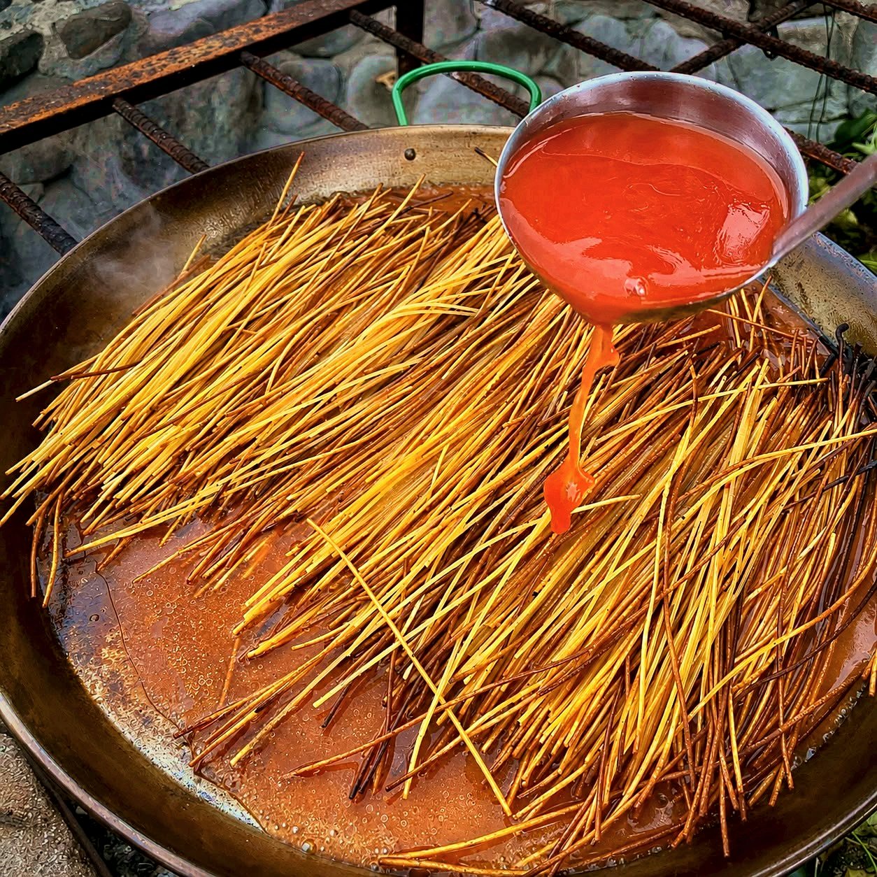 Spaghetti all'assassina charring in a carbon steel pan as dry strands fry in olive oil and concentrated tomato broth
